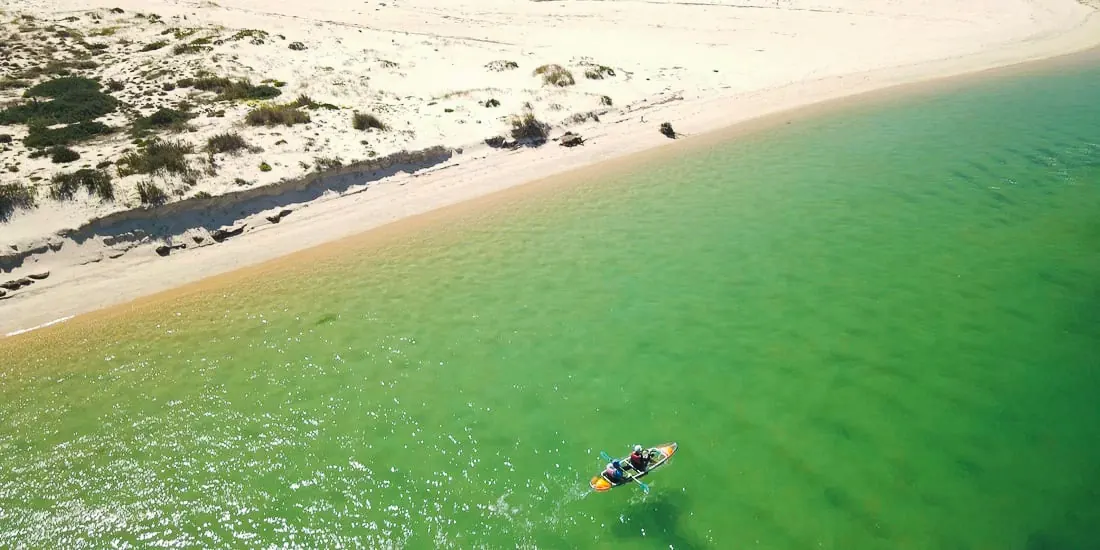 The white sand edge of a barrier island beside green water