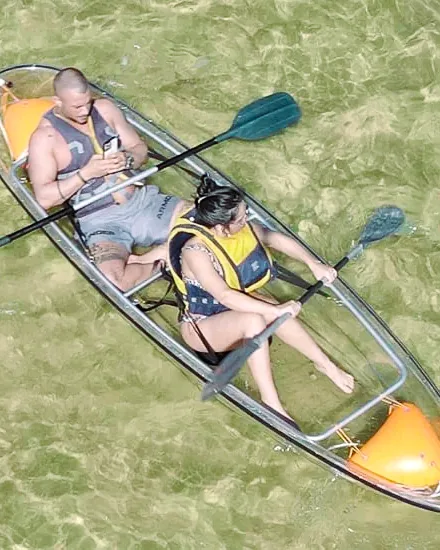 A couple in a transparent double kayak seen from directly above