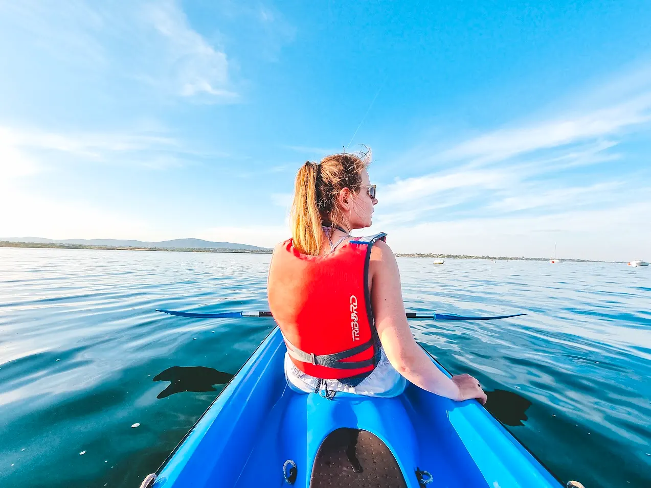 A paddler seen from behind, heading across the lagoon